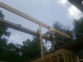 Carpenter setting a ridge beam over a new addition frame — Ice Dam Removal by Roofing Brothers in Leo