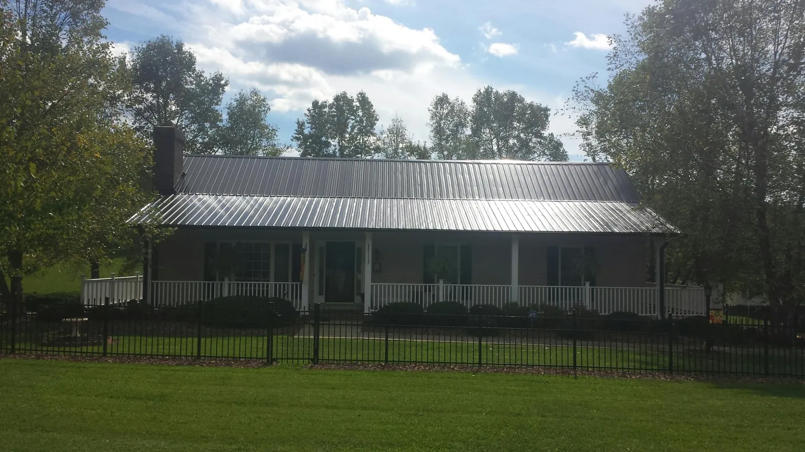 Gray metal roof on a brick ranch with a full width front porch — Gutter Guard Installation work by our crew in Leo