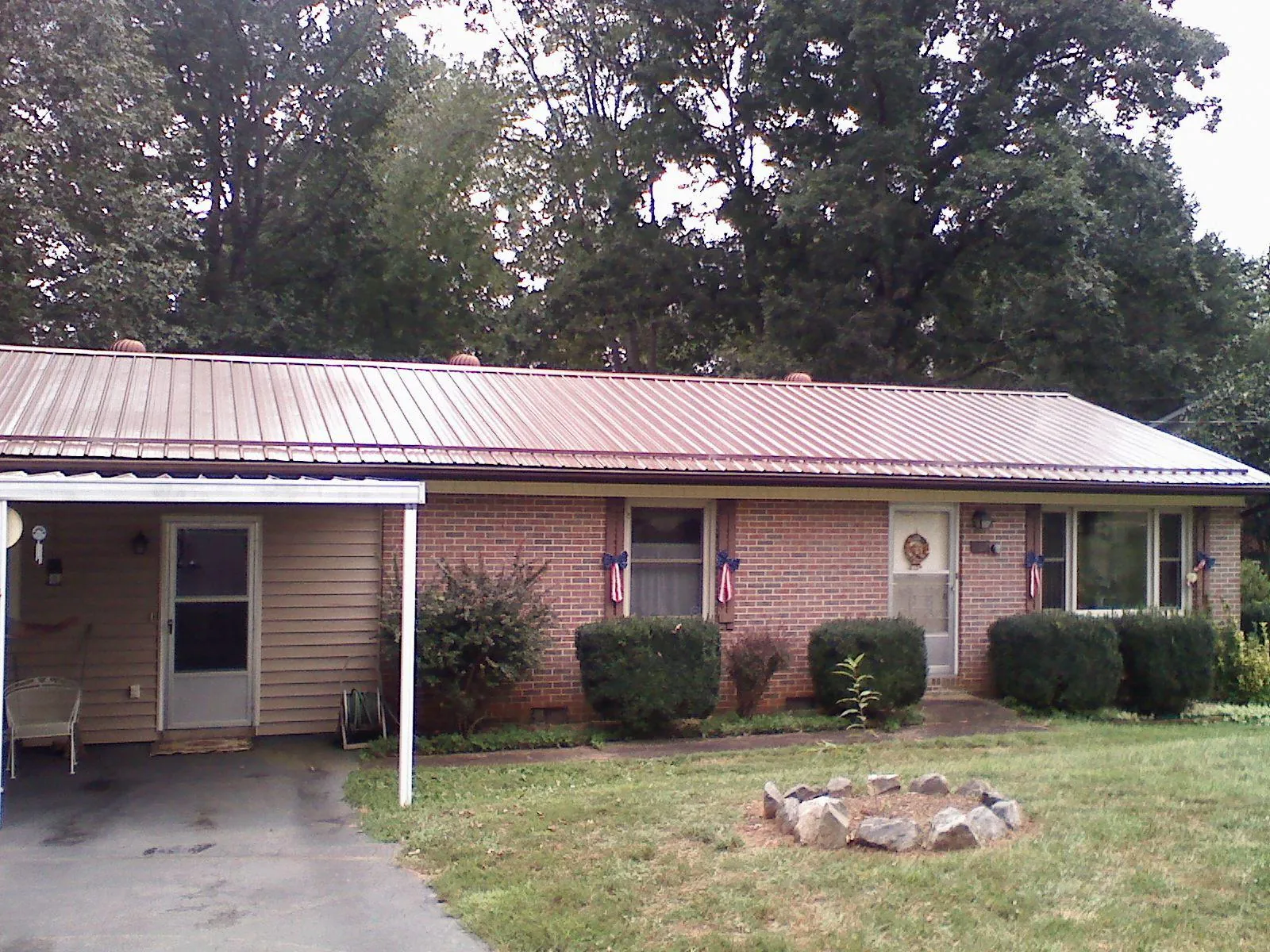 Bronze metal roof and carport on a brick ranch home — Roof Repair work by our crew in Leo